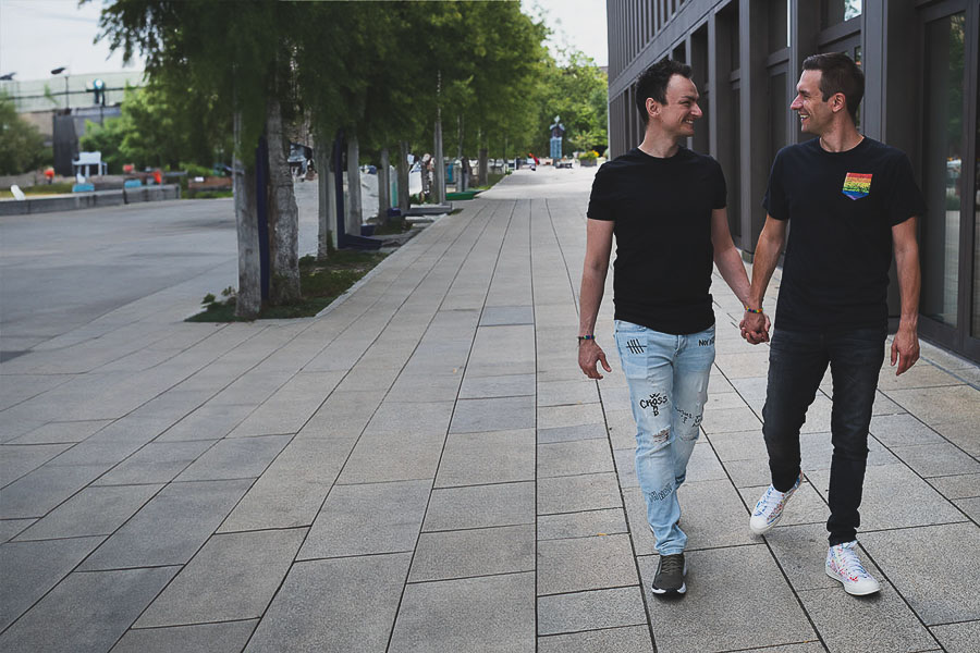 homosexuelles Männerpaar läuft händchenhaltend die Straße entlang