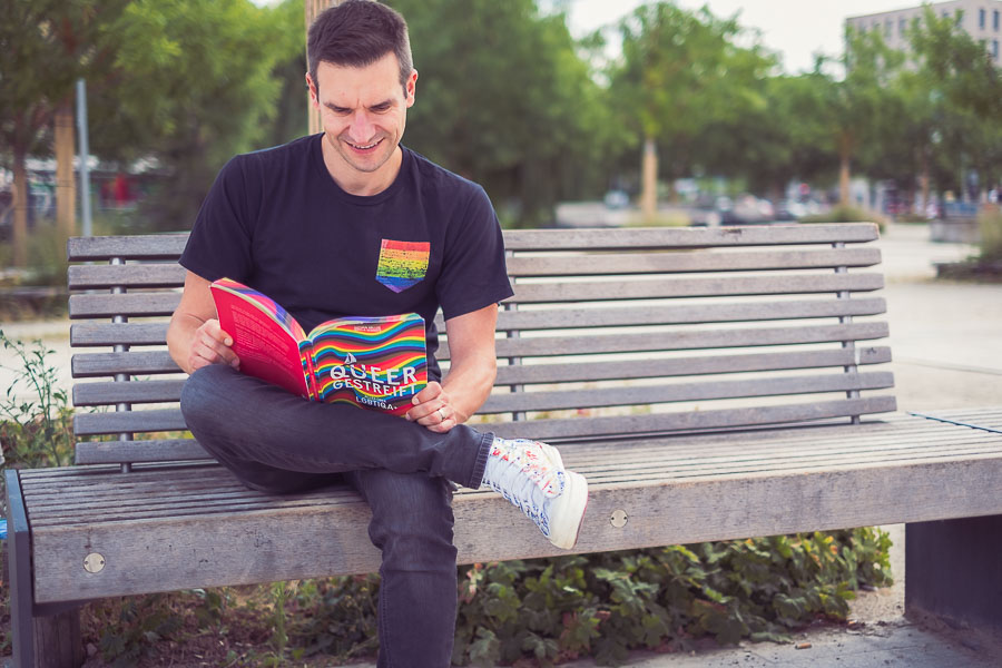 Schwuler Mann liest das Buch queer gestreift