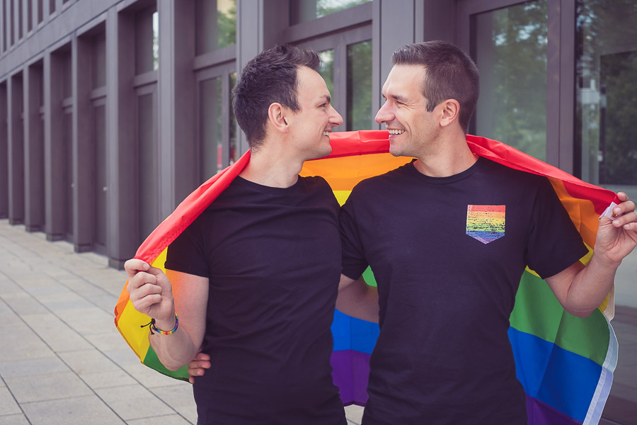 Zwei schwule Männer mit einer Regenbogenflagge schauen sich an